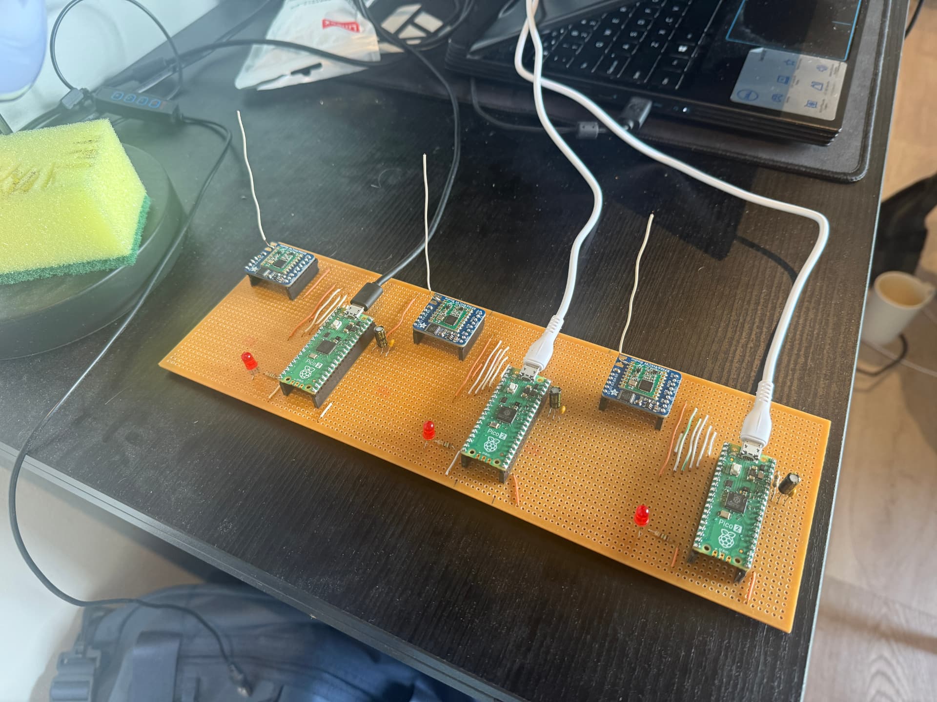 Prototype perfboard carrying four Raspberry Pi Pico 2 boards, RFM69HCW radio modules and wire antennas