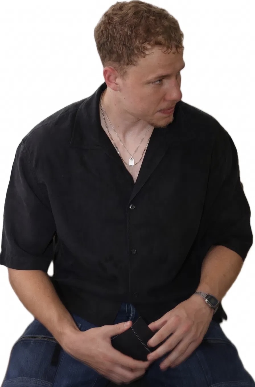 Portrait of Matteo Buxman in a black shirt, seated, looking to the side