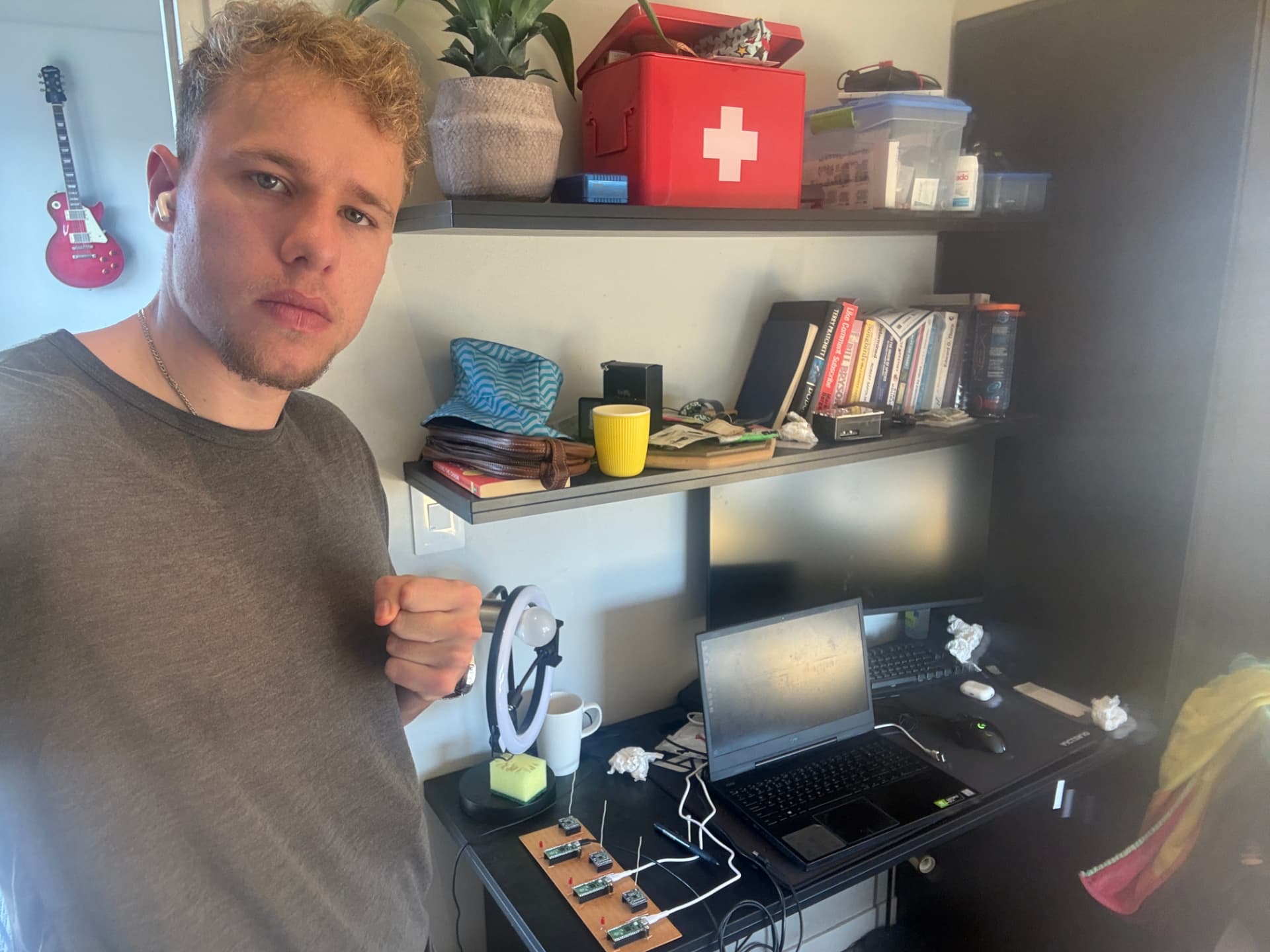 Matteo Buxman at his home desk beside a prototype radio node board and a laptop